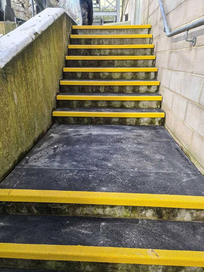 Worker installing GRP stair treads on industrial steps - finishings UK
