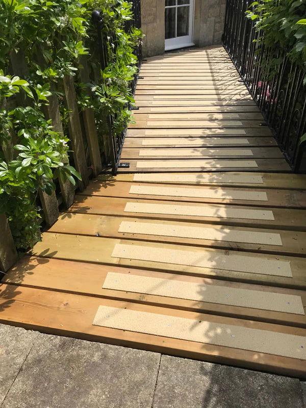 Installation of non-slip strips on wooden deck using screws. Non Slip Standard GRP Decking Strips skin color on wooden stairs- finishings UK
